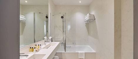 A modern bathroom with a glass-enclosed shower, a large bathtub, and a vanity with a mirror and sink.