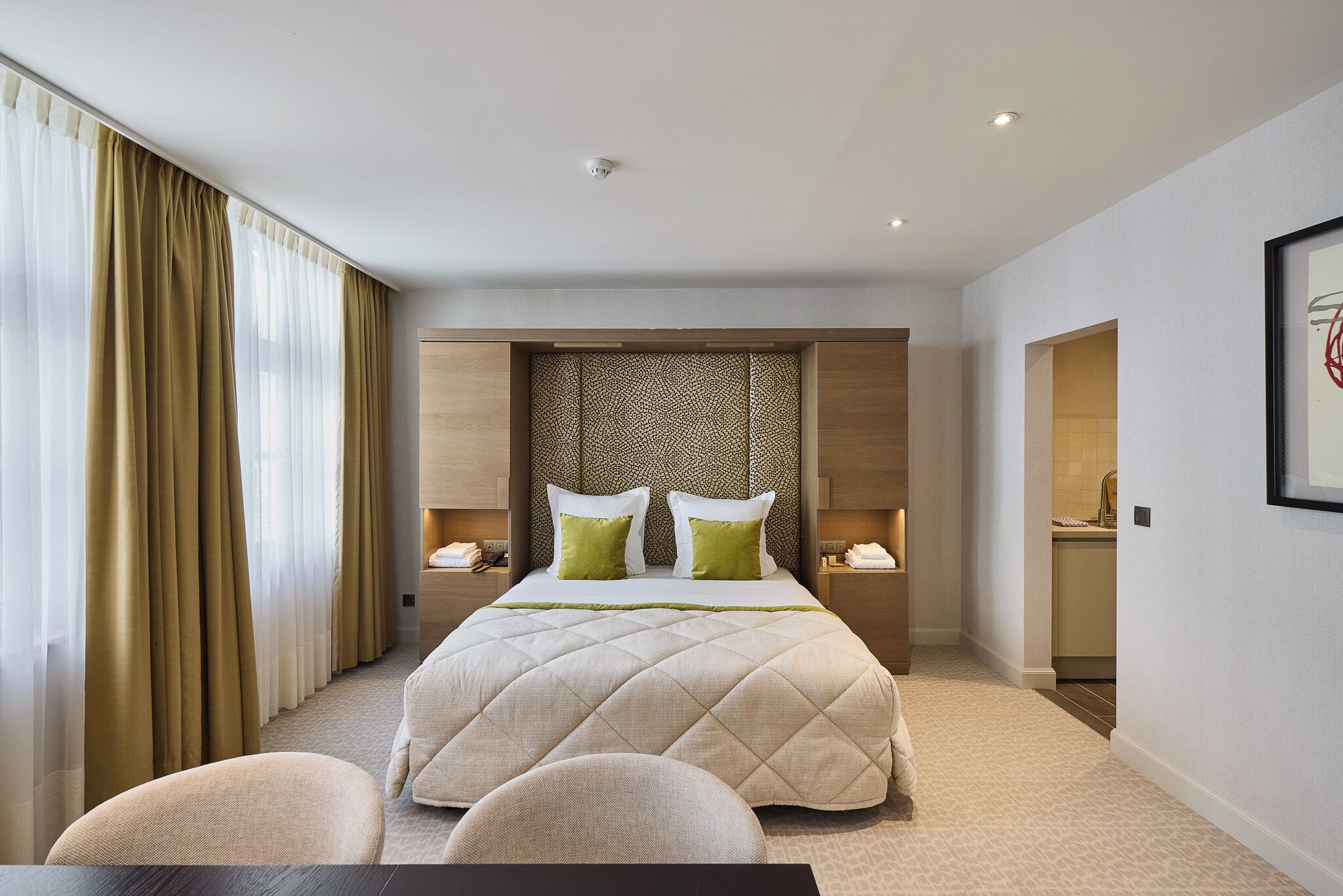 A hotel room with a large bed, two bedside tables, a desk, and a chair.