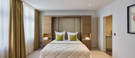 A hotel room with a large bed, two bedside tables, a desk, and a chair.