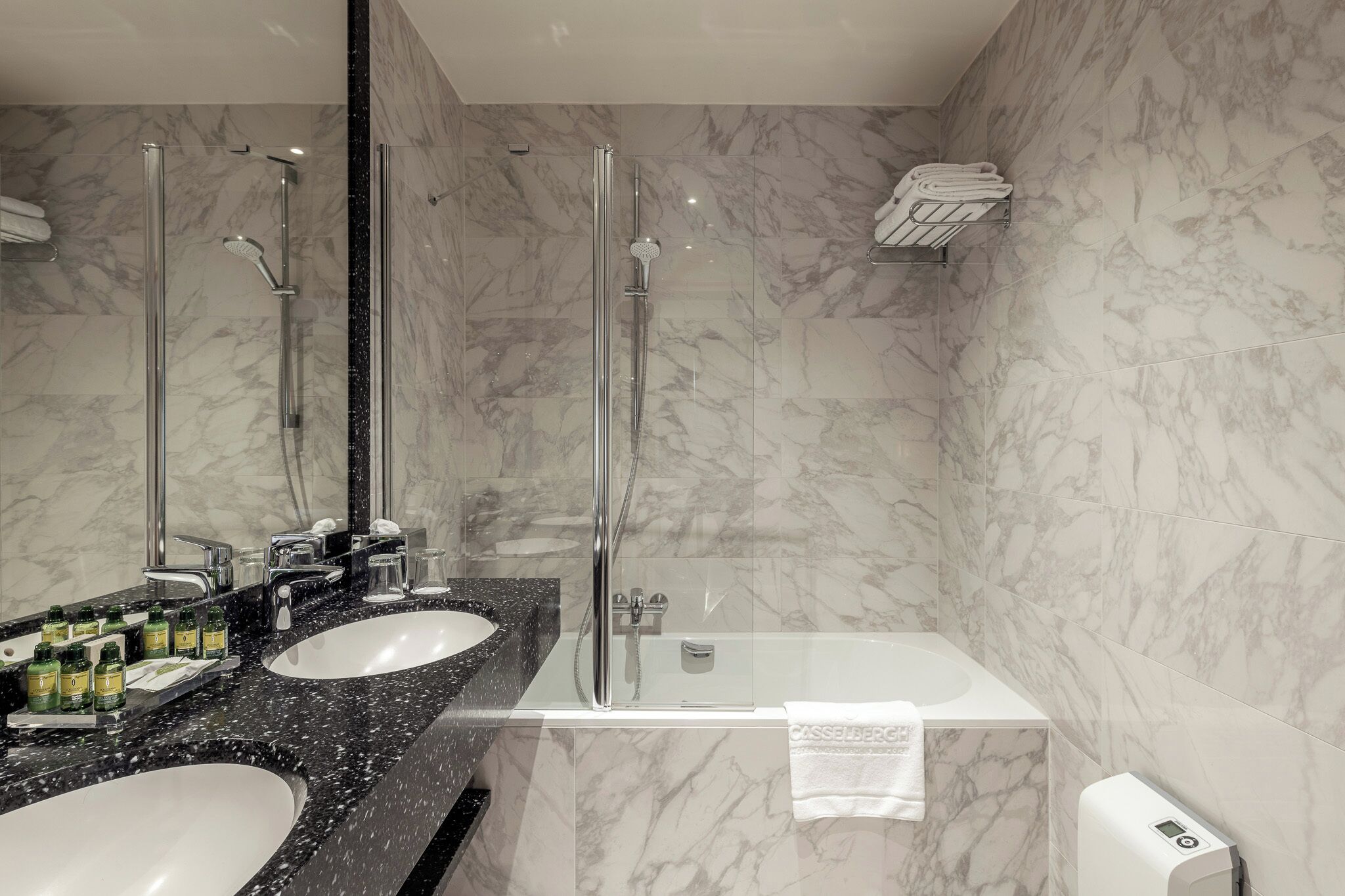 A modern bathroom with two sinks, a glass-enclosed shower, and a white bathtub.