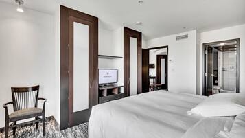 Une chambre d’hôtel avec un grand lit, une télévision, une chaise et une armoire.