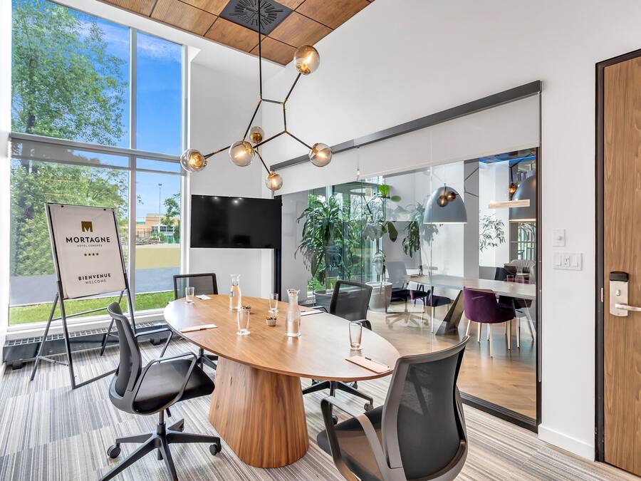A modern conference room with a large wooden table, black office chairs, and a sign reading "MORTGAGE Welcome".