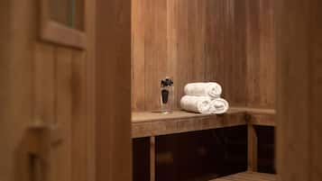Banco de madera en un sauna, con toallas y una botella de agua.