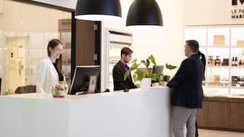 A reception area with a white counter, a computer, and a potted plant.