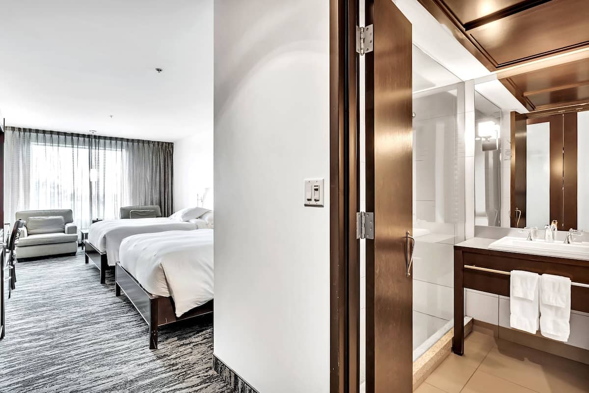 Una habitación de hotel con cama, sofá, baño con espejo y ducha.