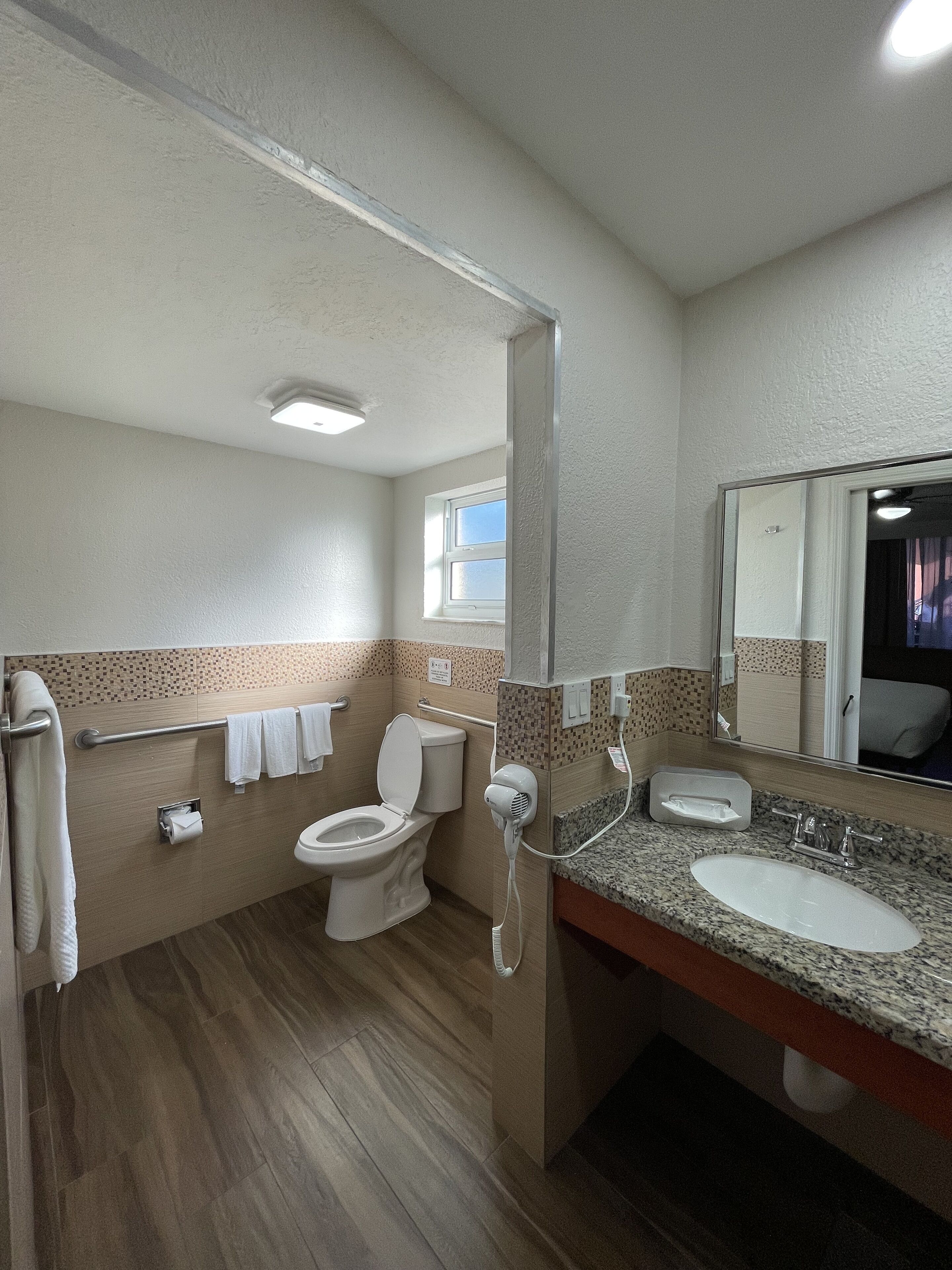 A bathroom with a toilet, sink, and mirror.