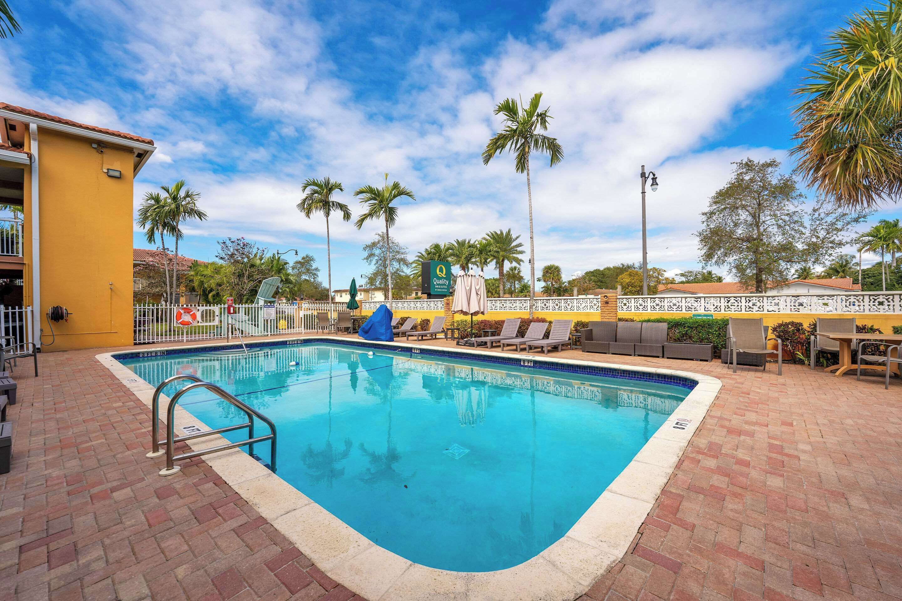Una piscina al aire libre, sombrillas, sillones reclinables de piscina