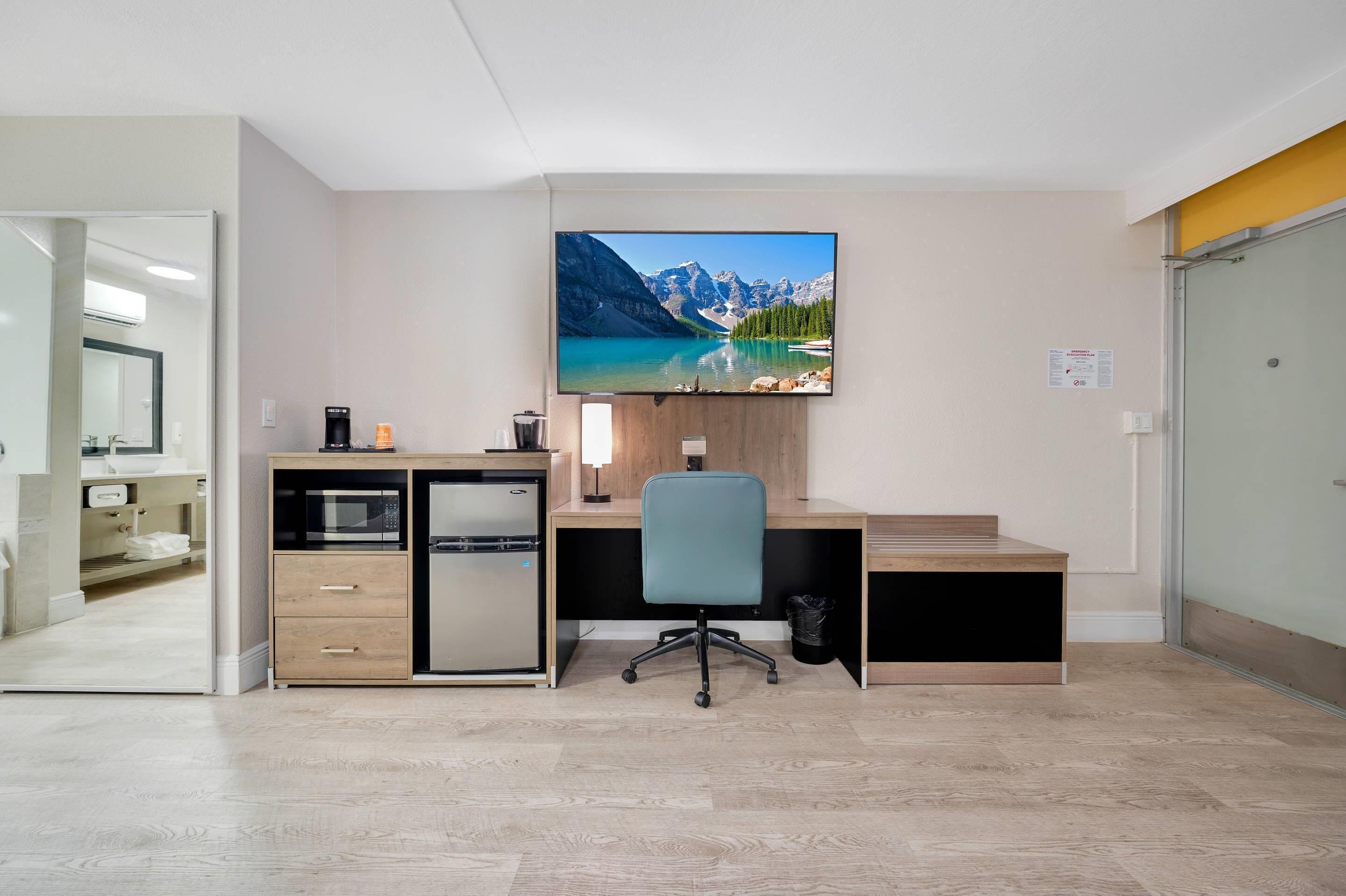 A modern office space with a desk, chair, and a large flat-screen TV mounted on the wall.