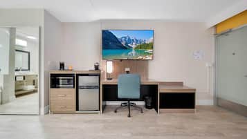 A modern office space with a desk, chair, and a large flat-screen TV mounted on the wall.
