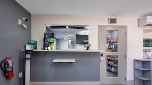 A reception desk with a digital clock, a fire extinguisher, and a snack vending machine. - Quality Inn & Suites Airport/Cruise Port Hollywood (Hollywood)