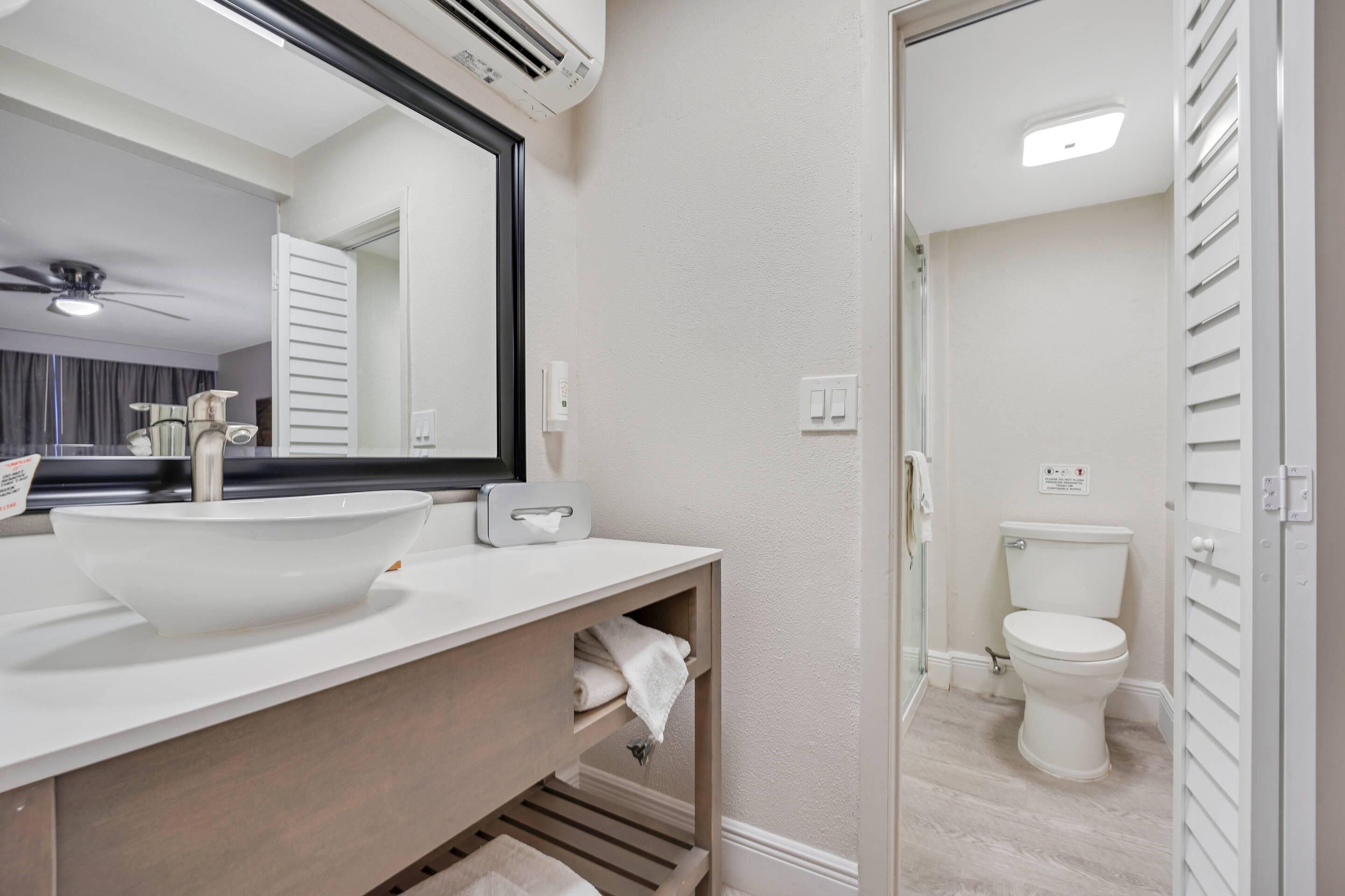 A modern bathroom with a white sink, mirror, and toilet.