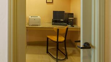 Un petit bureau avec un bureau, une chaise, une imprimante et un ordinateur.