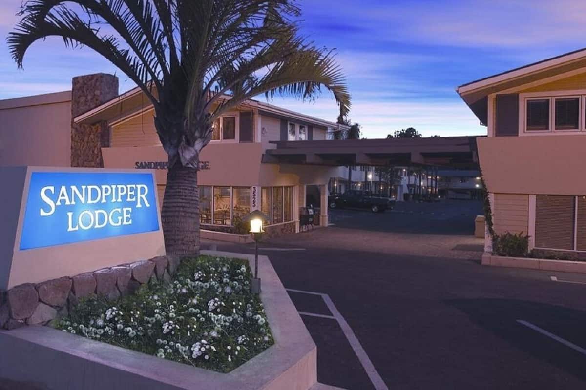 The Sandpiper Lodge entrance with a sign, palm trees, and a parking lot.