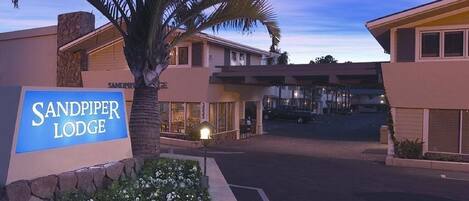 The Sandpiper Lodge entrance with a sign, palm trees, and a parking lot.