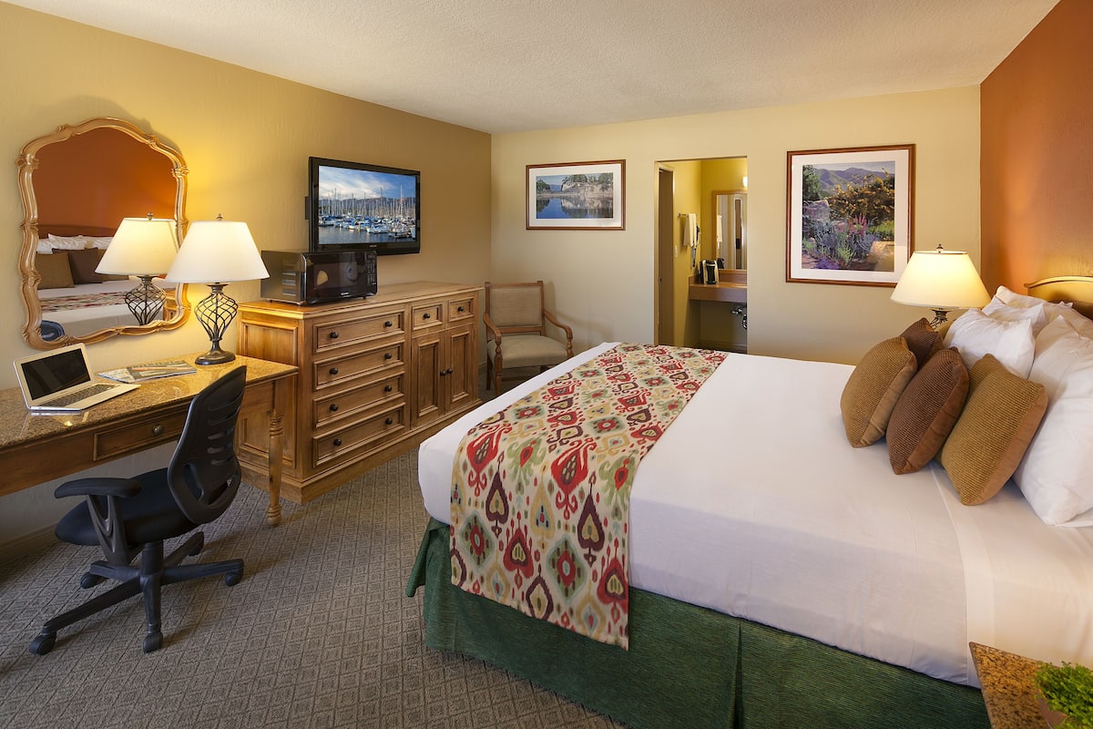 A hotel room with a bed, desk, chair, and television.