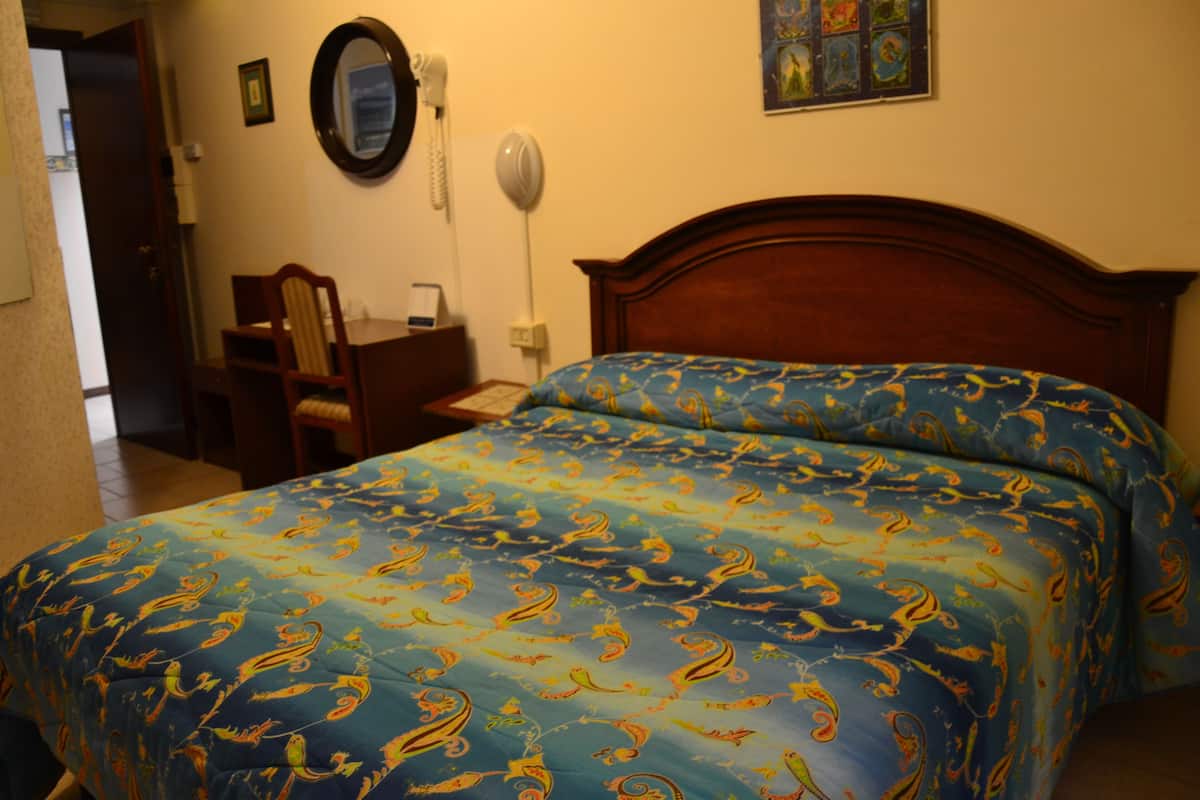 A hotel room with a bed, a desk, and a chair.