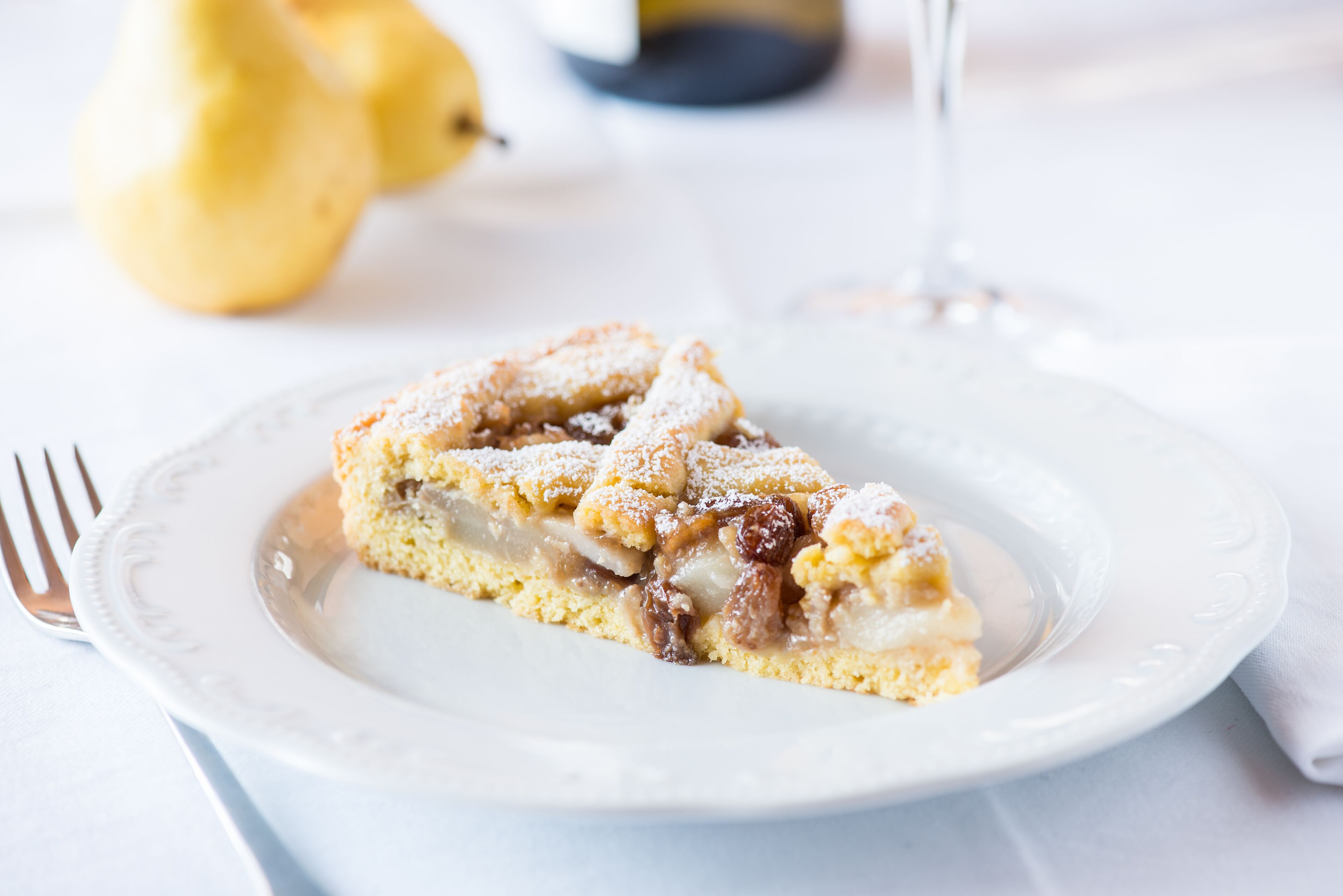 A slice of apple pie on a white plate with a fork beside it.