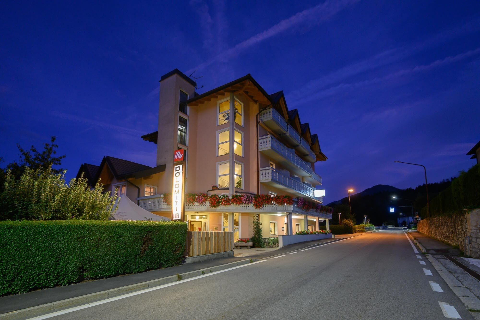Ein Hotel mit einem Schild, auf dem 'DOLOMITI HOTEL' steht, und Balkonen mit Blumenkästen.