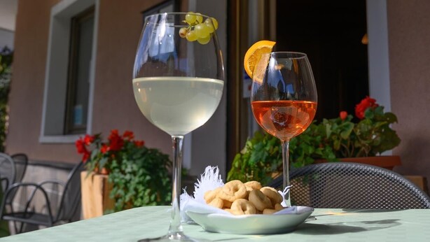 A restaurant with a sign reading "RISTORANTE" and two glasses of wine on a table with a plate of snacks.