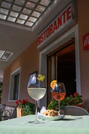 Un restaurante con un letrero que dice 'RISTORANTE' y dos copas de vino sobre una mesa con un plato de aperitivos.
