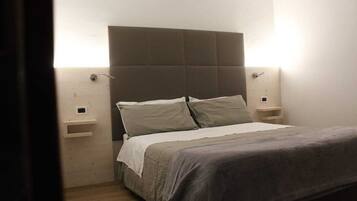 Quarto com cama, mesas de cabeceira e cabeceira.