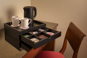 Een klein koffiehoekje met twee witte kopjes, een zwarte koffiepot en een dienblad met diverse spullen.