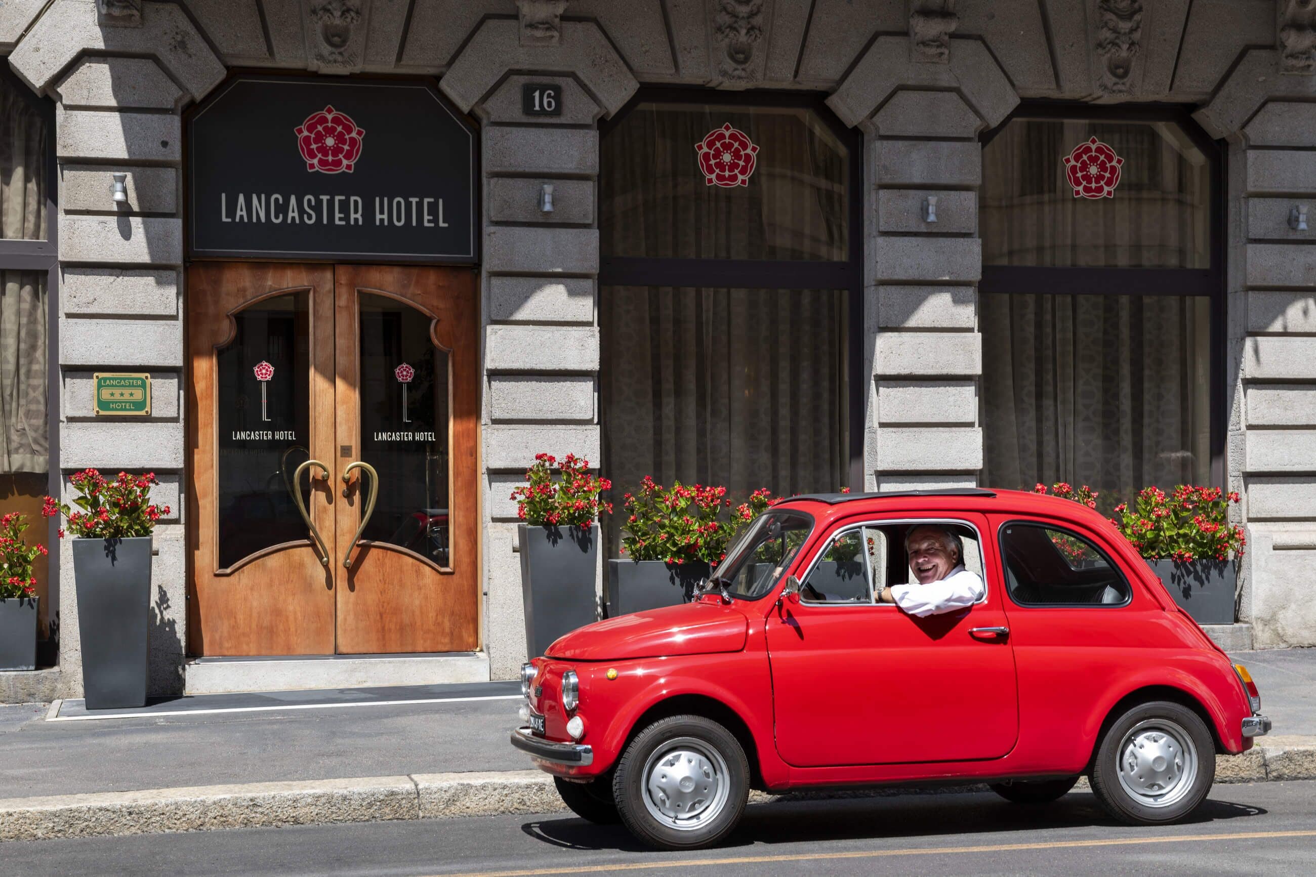Um carro vintage vermelho estacionado em frente ao Lancaster Hotel.