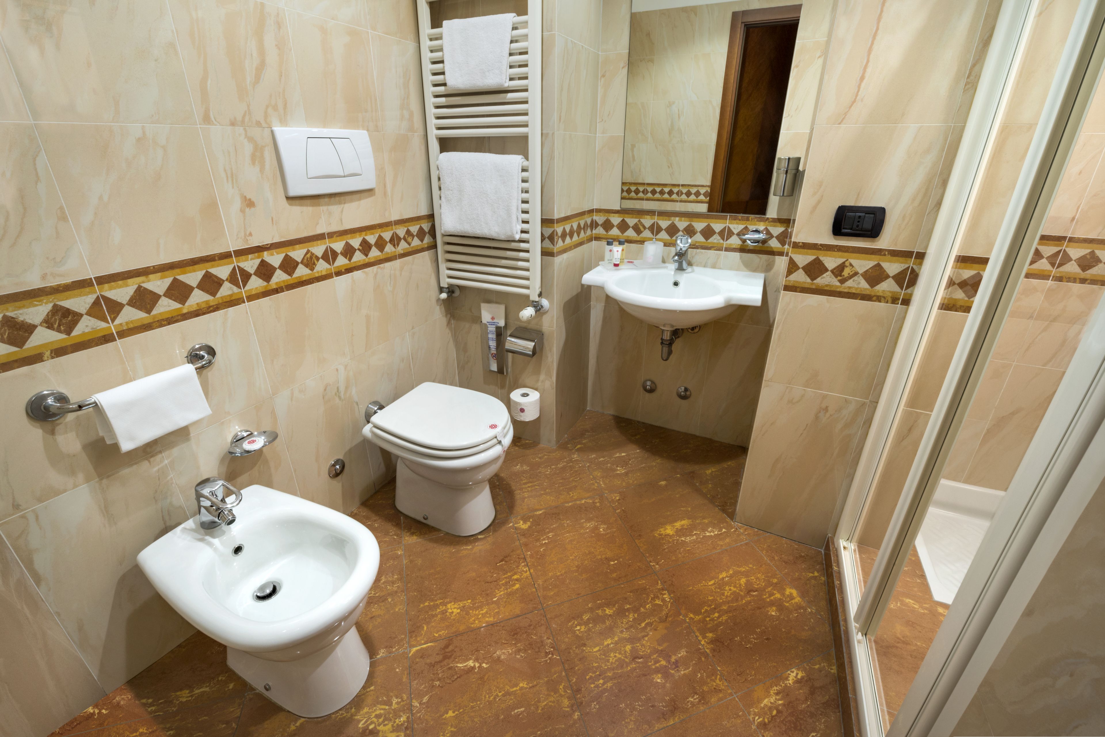 Un baño con bidé, inodoro, lavabo y perchero para toallas.