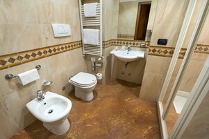 A bathroom with a bidet, toilet, sink, and towel rack.