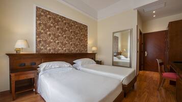 Ein Hotelzimmer mit einem großen Bett, zwei Nachttischen, einem Spiegel, einem Holzschrank und einem Sessel.