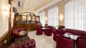 A bar area with a wooden counter, red leather seating, and a tiled floor. - Lancaster Hotel (Milan)