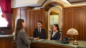 A reception desk with wooden paneling, a telephone, and a lamp. - Lancaster Hotel (Milan)