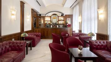 A bar area with red leather seating, a bar counter, and a mirrored wall.