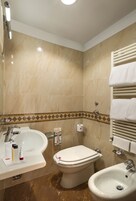 A bathroom with a sink, toilet, and bidet.