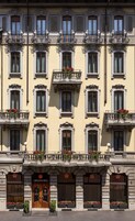 A multi-story hotel with ornate balconies, large windows, and flower boxes.