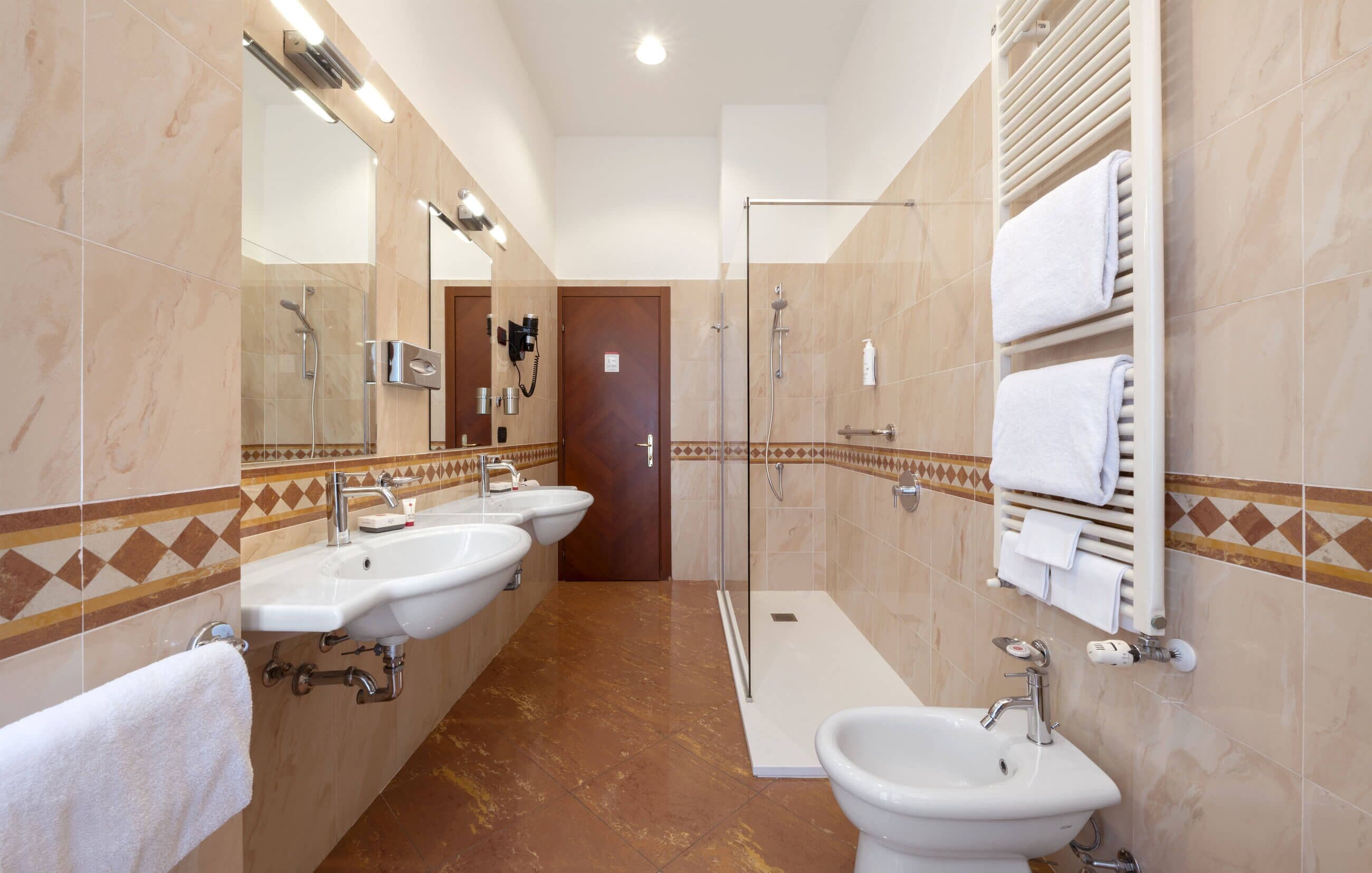 Un baño moderno con dos lavamanos, una ducha y un inodoro.