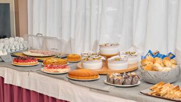 A buffet table with various food items including cakes, pastries, and bread.