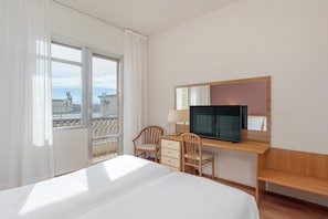 A hotel room with a bed, a desk with a television, a chair, and a window with a view of the city. - B&B Hotel Celle Ligure (Celle Ligure)