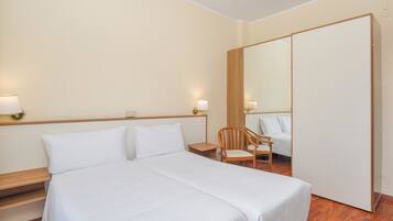 Ein Hotelzimmer mit einem großen Bett, einem Holzstuhl, einem Nachttisch und einem Spiegel.