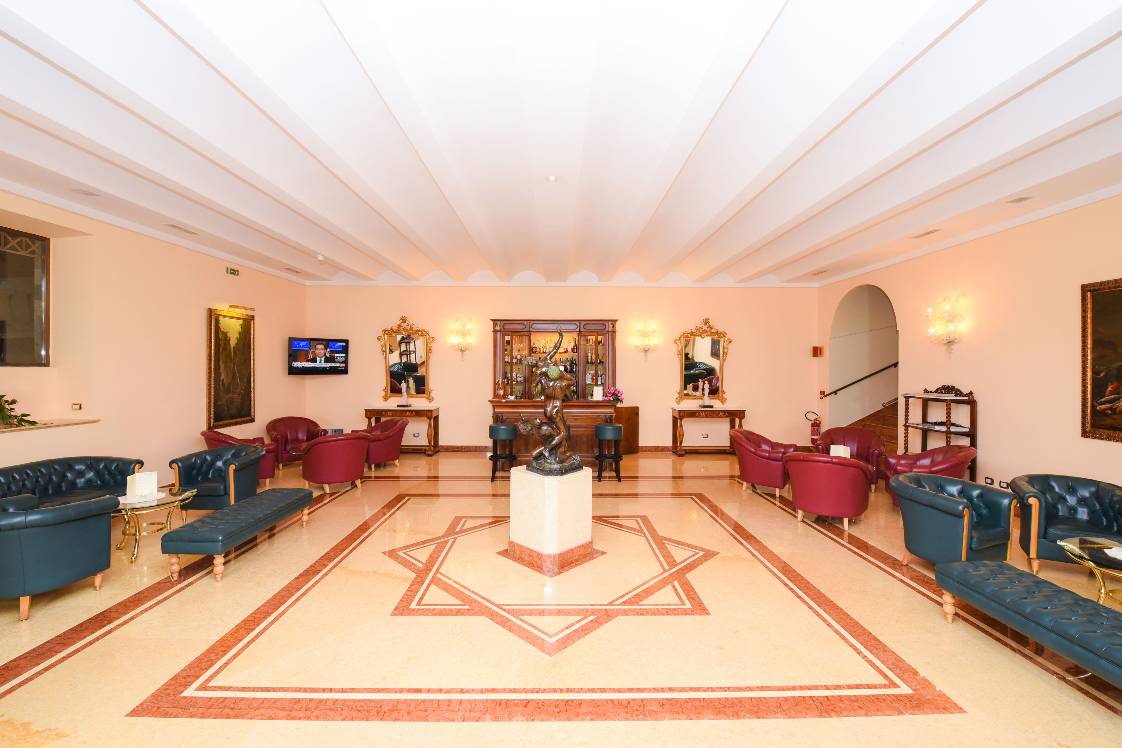 A spacious lobby with a central statue, multiple seating areas, and a television.