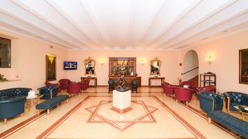 A spacious lobby with a central statue, multiple seating areas, and a television.