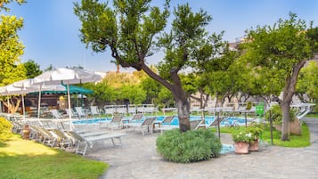 Relax by the pool surrounded by lush trees and comfortable lounge chairs.