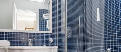 A bathroom with a white sink, a shower with a glass door, and blue-tiled walls.