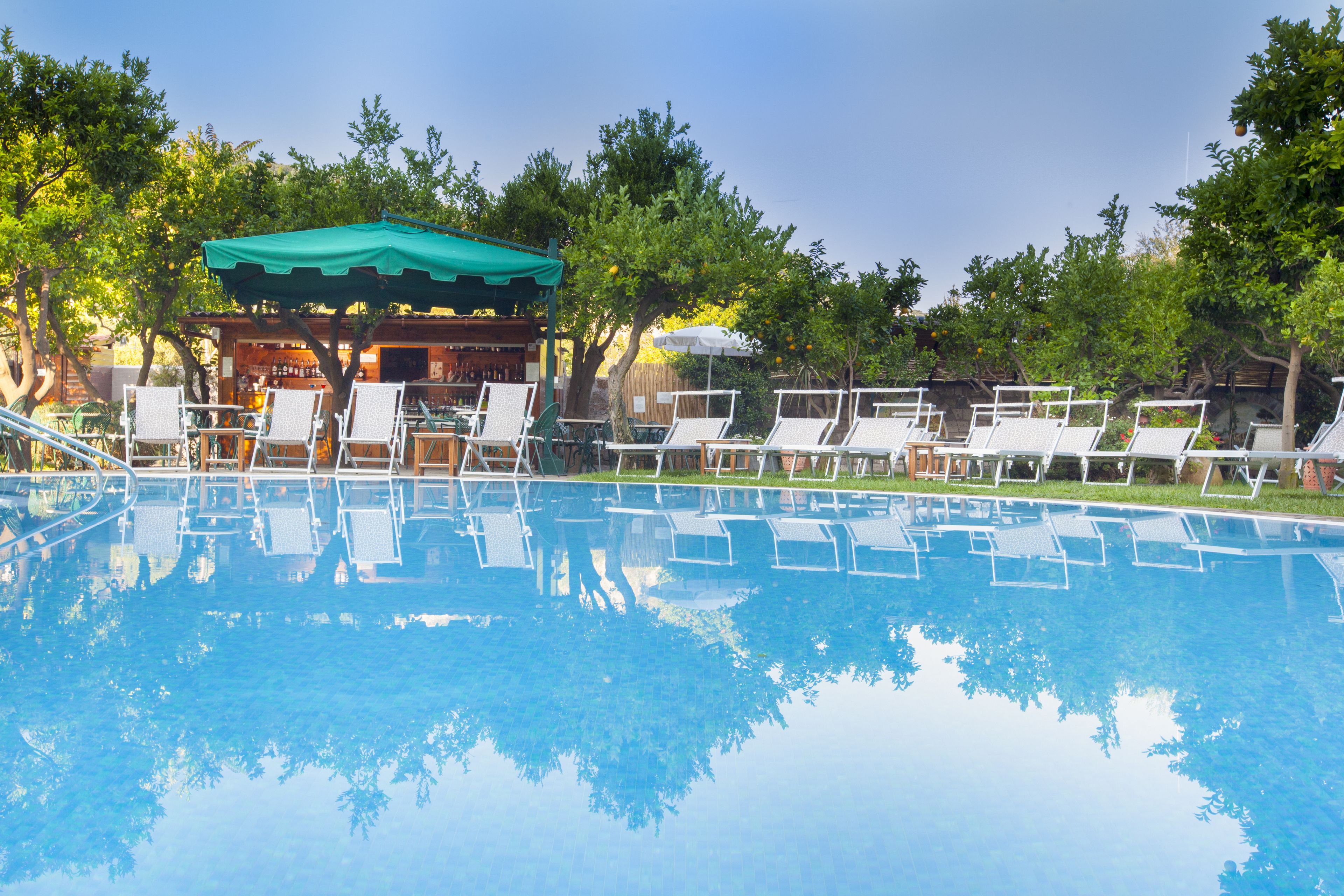 Une piscine avec des chaises longues et un espace ombragé.