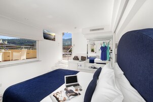 Habitación de hotel moderna con una cama grande, una computadora portátil y vistas a las montañas.