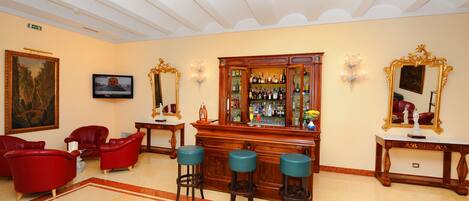 Zona de bar con muebles de madera, un televisor y un espejo grande.