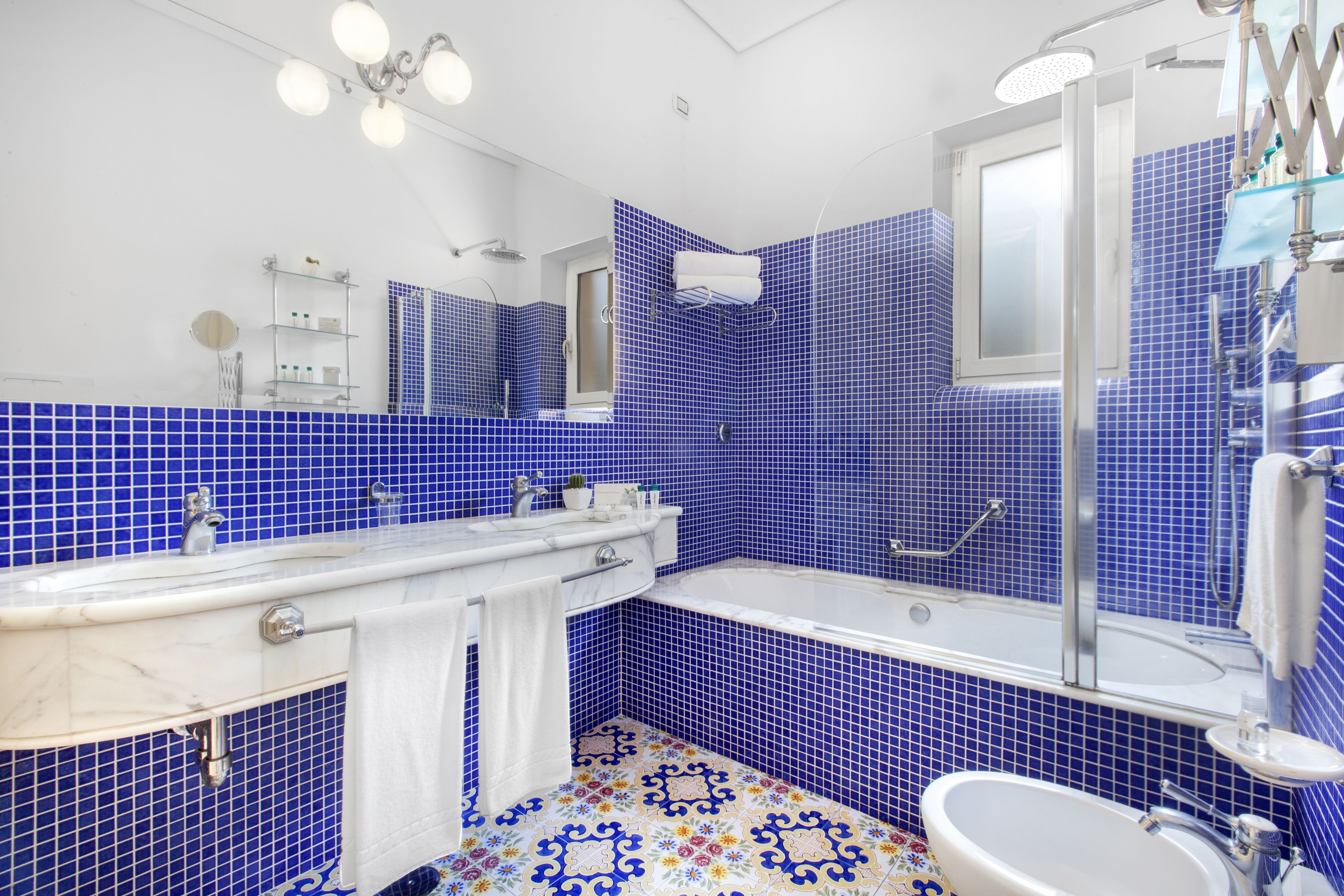 A bathroom with blue tiled walls, a white sink, and a bathtub.