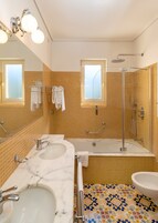 A bathroom with two sinks, a bathtub, a shower, and a toilet.