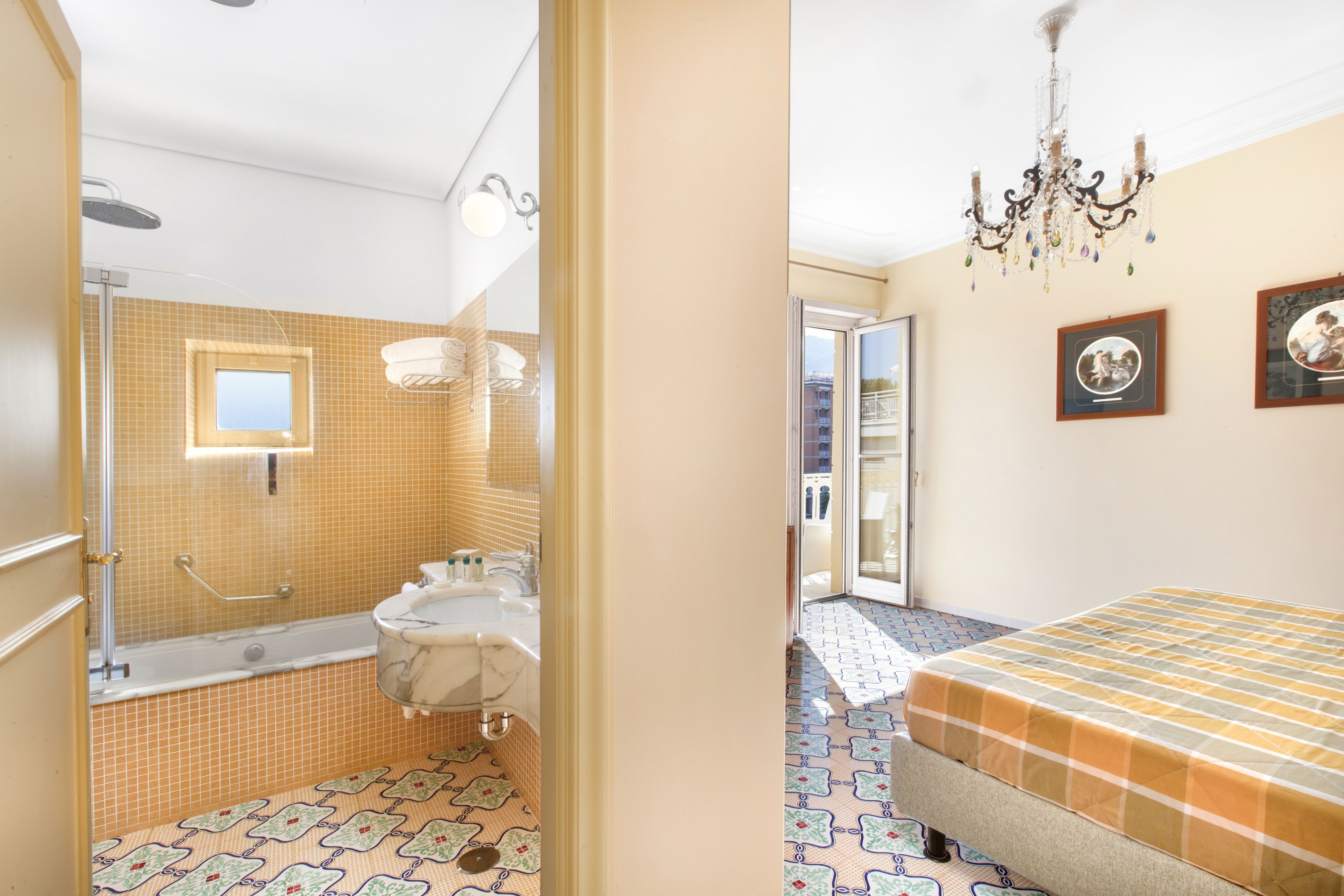 Un baño con bañera, ducha y lavamanos, y un dormitorio con cama y candelabro.