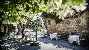Un espace de restauration en plein air, avec des tables et des chaises, entouré de murs en pierre et de verdure.